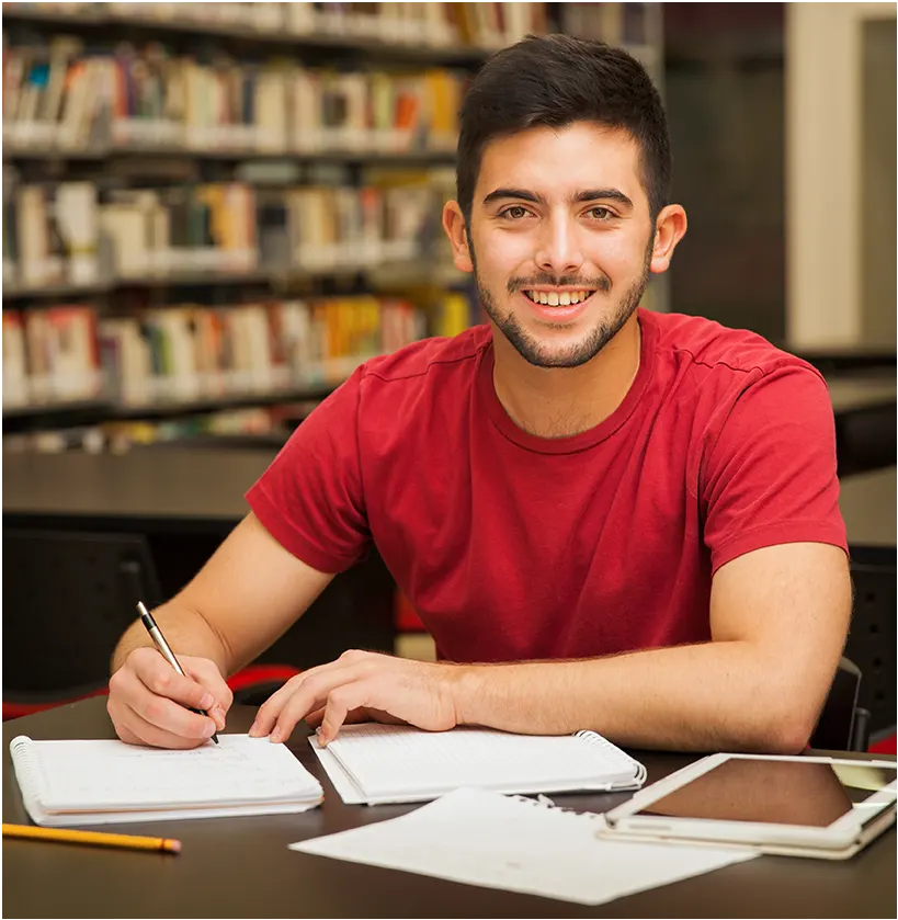 attractive-male-university-student-doing-some-homework-school-library-smiling
